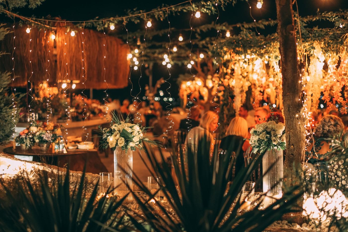 Night garden party glowing under layers of warm string lights
